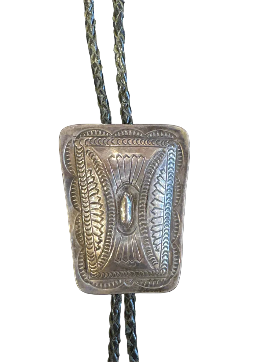 Silver bolo tie with intricate design on a white background
