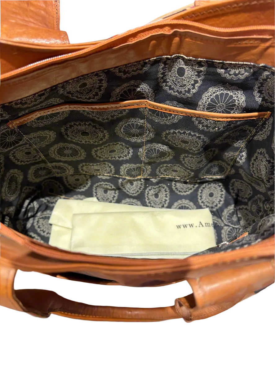 Brown leather tote bag with decorative handles on a white background