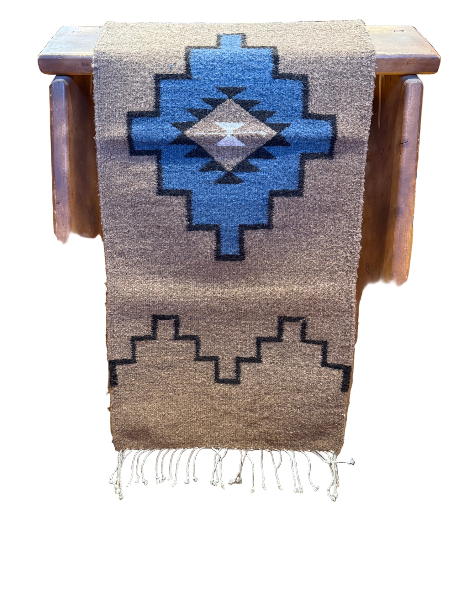 Woven blanket with geometric pattern on a wooden stool
