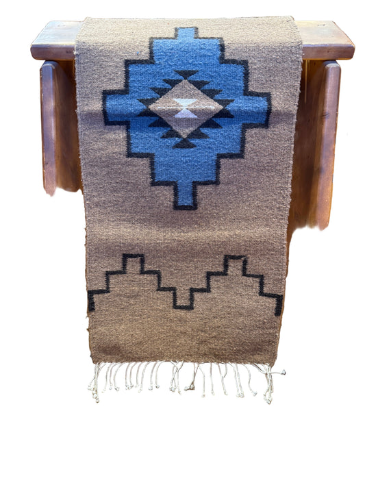 Woven blanket with geometric pattern on a wooden stool