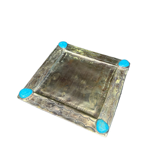 Decorative square metal box with turquoise knobs on a patterned fabric background