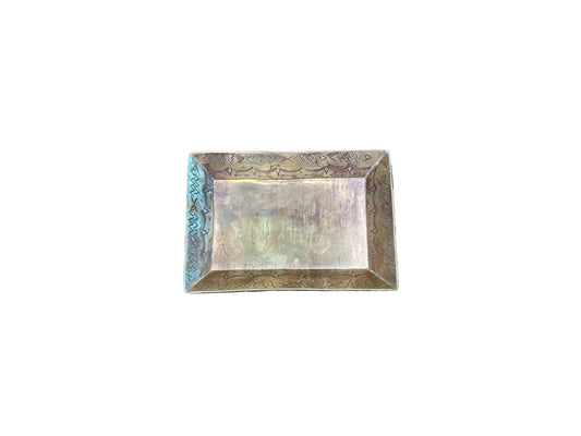Decorative silver tray on a patterned fabric background